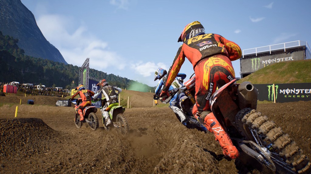Corsa di motocross con diverse moto su un tracciato di terra, pubblico in lontananza.