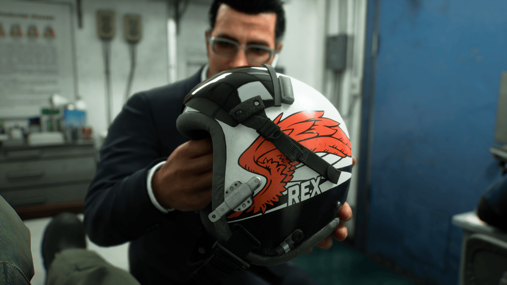 Un uomo in giacca afferra un casco decorato con un'illustrazione di un uccello rosso e la scritta 'REX'.