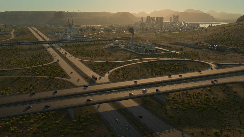 Panorama di un paesaggio urbano con strade e autostrade, impianti industriali e edifici sullo sfondo, illuminato dalla luce del sole al tramonto.